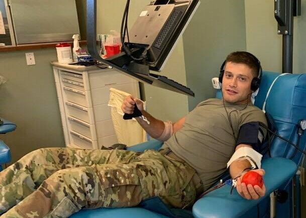 A service member sits in chair to donate blood