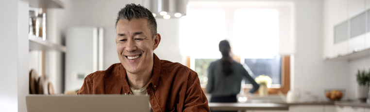Man smiling and typing on laptop